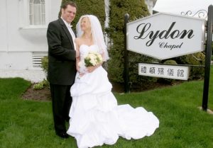 couple outside lydon chapel by sign
